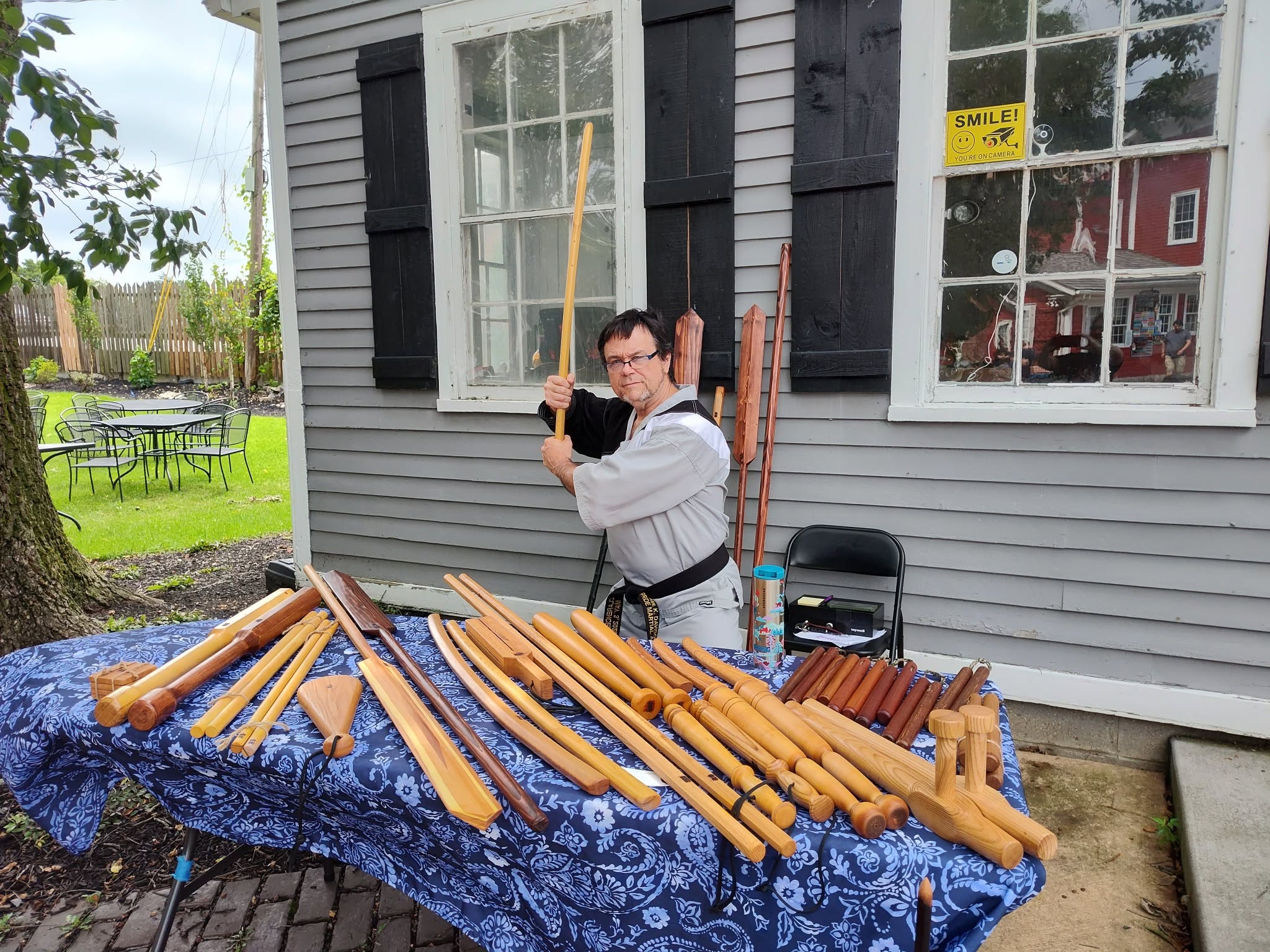 Martial artist with a large selection of wooden training weapons displayed on a table